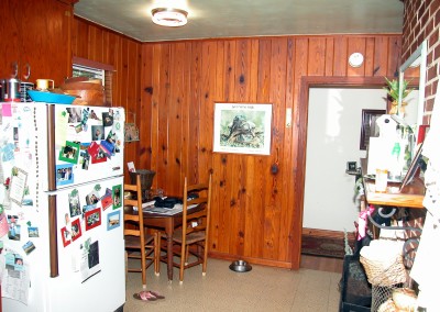 Vieww of wood paneled wall, refrigerator and old kitchen table